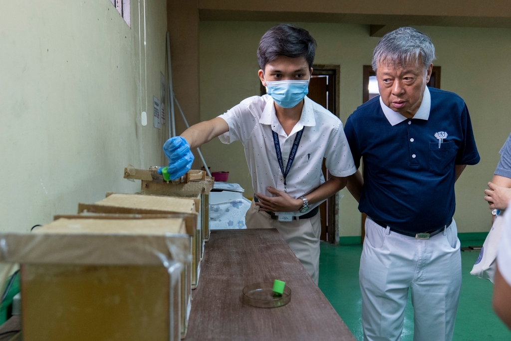 Chemical engineer Ace Angeles (left) shows Tzu Chi volunteer Johnny Kwok the plastic caps that serve as biofilm carriers.