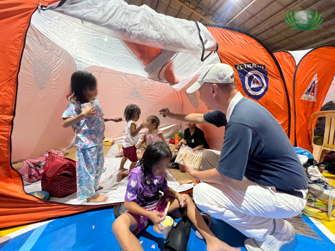 Volunteer Luis Diamante distributes breadsticks to children in a modular tent.