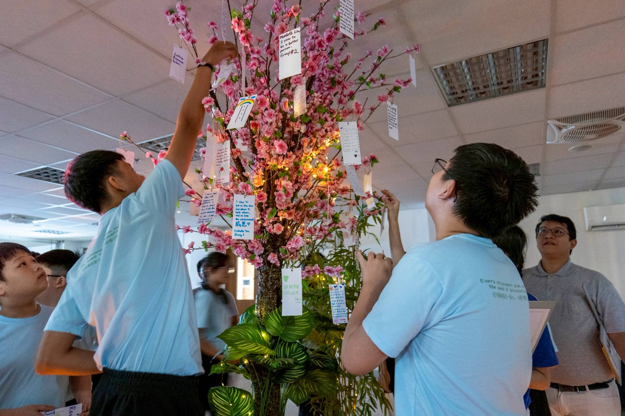 Campers hang their handwritten vows on the branches of a flower tree. 