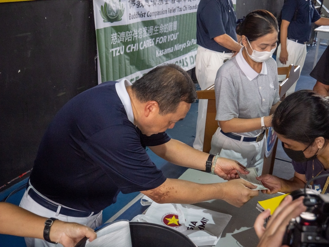 Tzu Chi volunteer Benson Lao (left) distributes Puregold gift vouchers for beneficiaries’ personal needs.