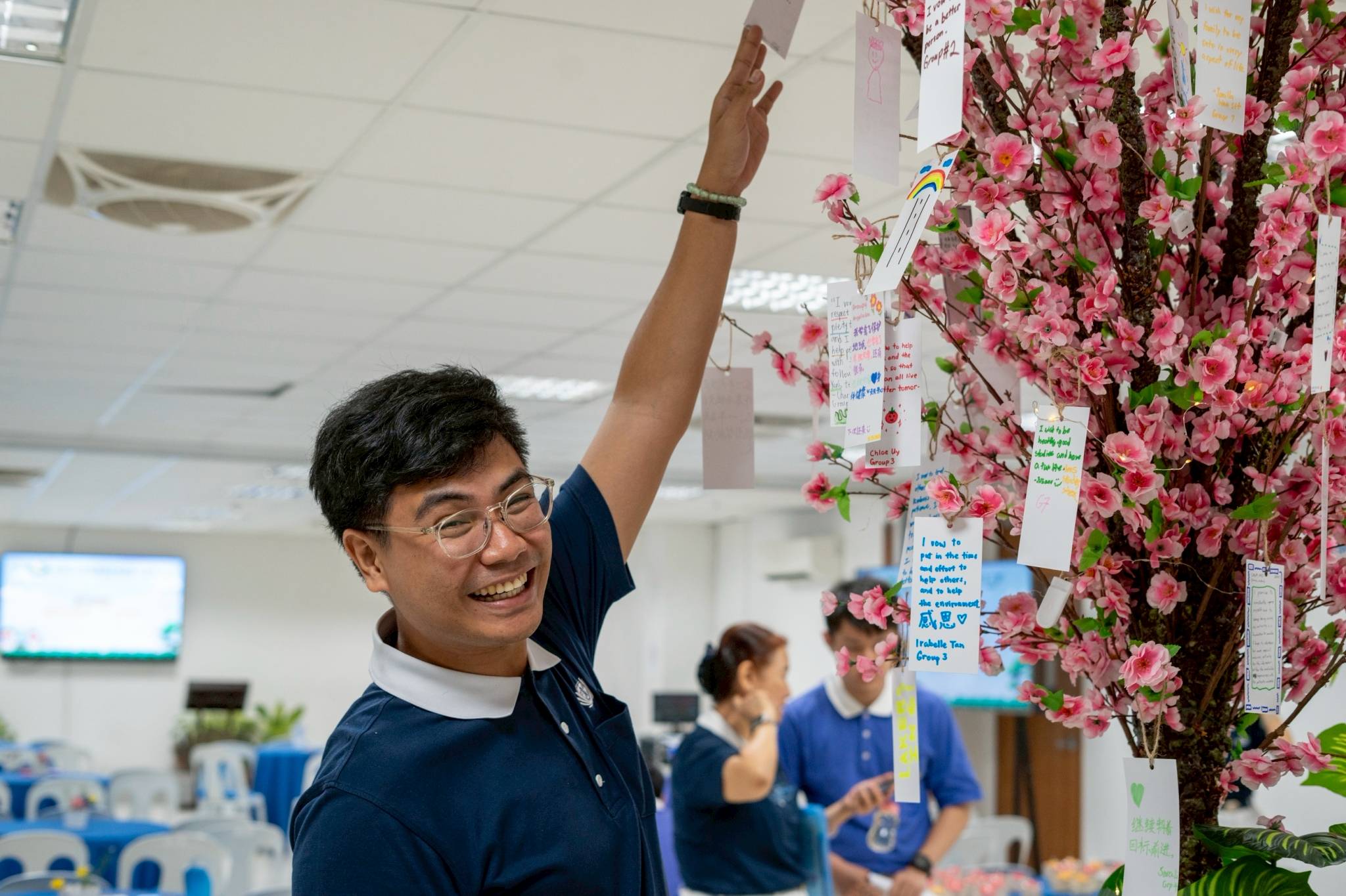 Tzu Chi Zamboanga volunteer Dhing Abdulaup reaches for vows written and hung by campers. 