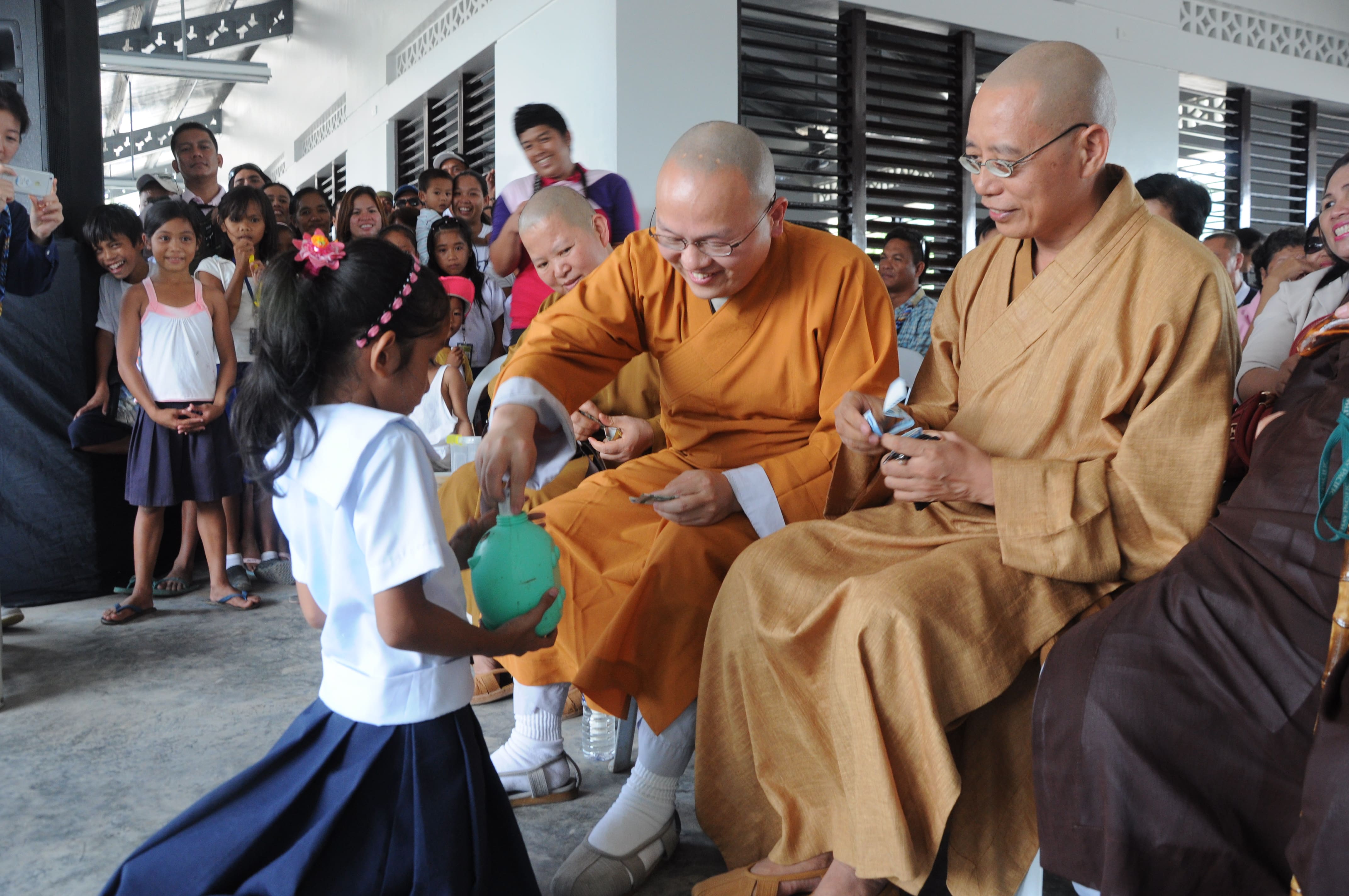 Buddhist monks from Long Hua Temple in Davao City donate to a child’s piggy bank during the turnover ceremony of Mangayon Elementary School on December 1, 2014.