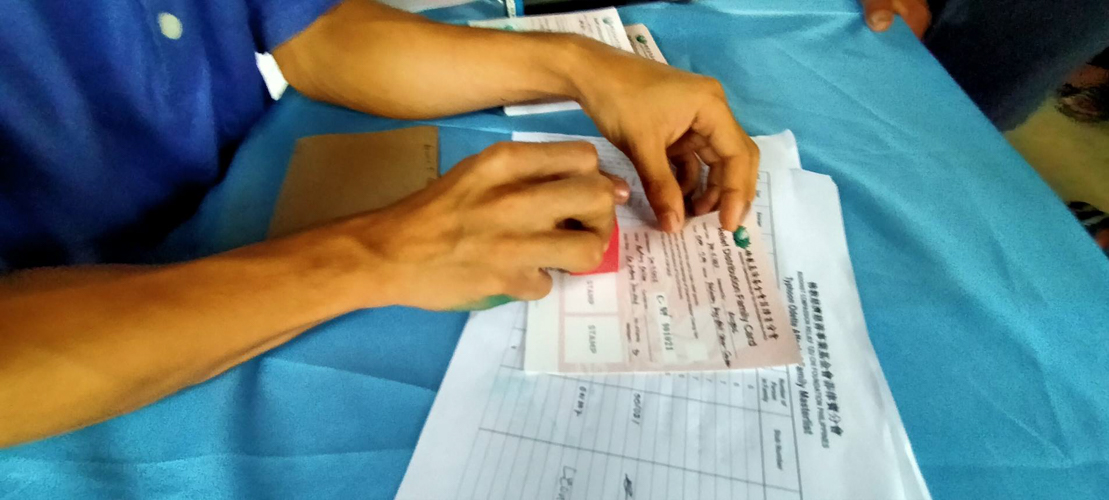 A volunteer stamps a beneficiary’s relief card. 