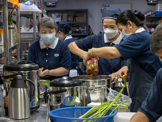 Volunteers tolerate the heat of a hot and crowded kitchen to prepare delicious vegetarian meals for guest.【Photo by Matt Serrano】