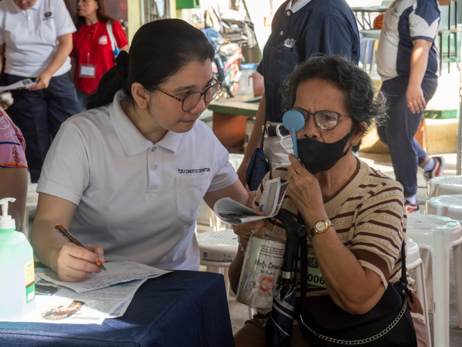 A volunteer assists a patient in a visual acuity test. 
