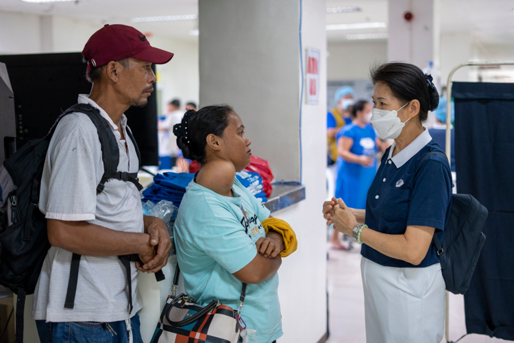 Tzu Chi Philippines Deputy CEO Woong Ng (right) talks to a woman with goiter. Volunteer surgeons performed 35 thyroidectomies at the Palo medical mission.