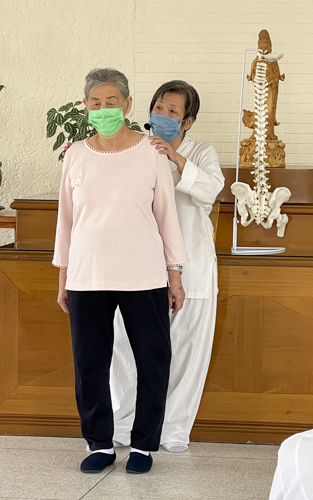 Teacher Bee (in white) guides a student during a Zhineng Qigong (智能氣功)class for beginners.  