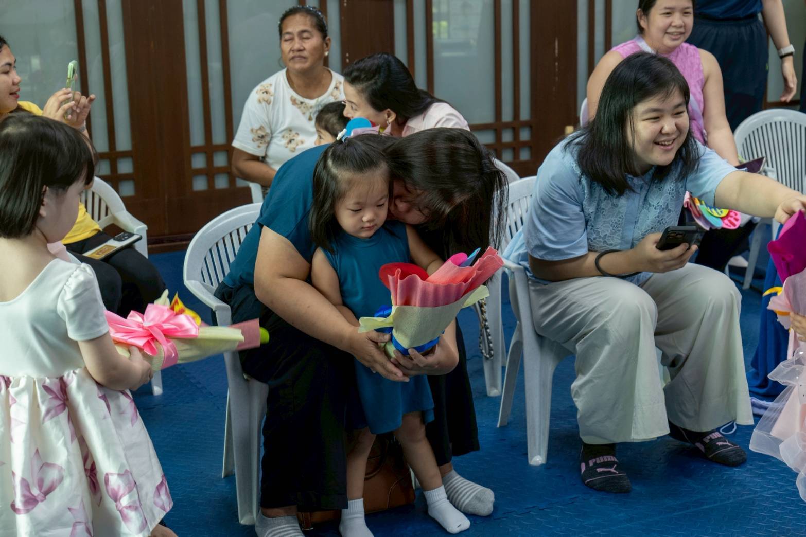In a touching moment, a  mother gives her child a tight hug after receiving a special handmade  bouquet of flowers as a token of love. 