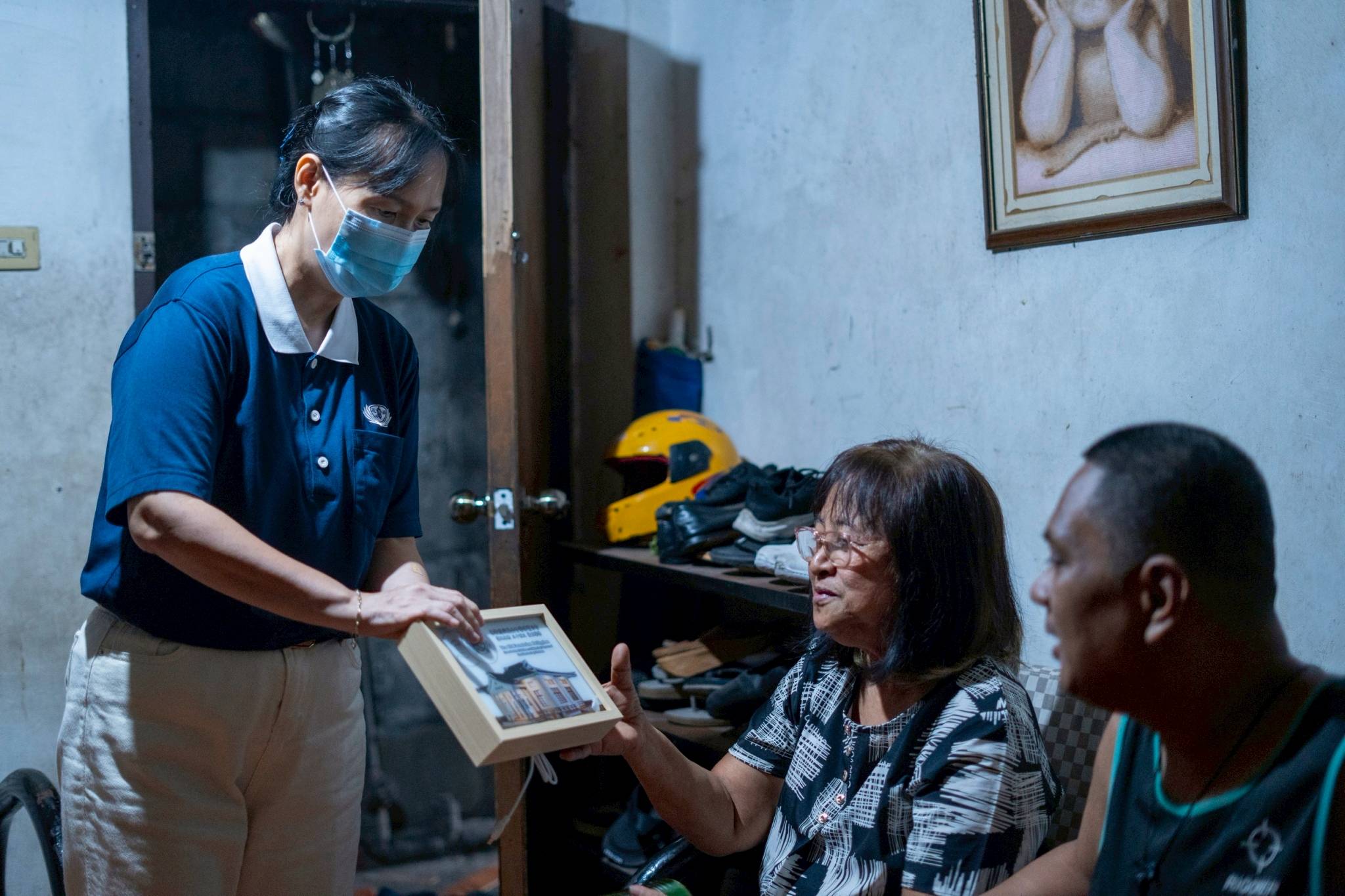 Tzu Chi volunteer Amy Chan presented the family with a commemorative lamp frame and coin cans as a reminder to nurture a culture of giving and compassion. 