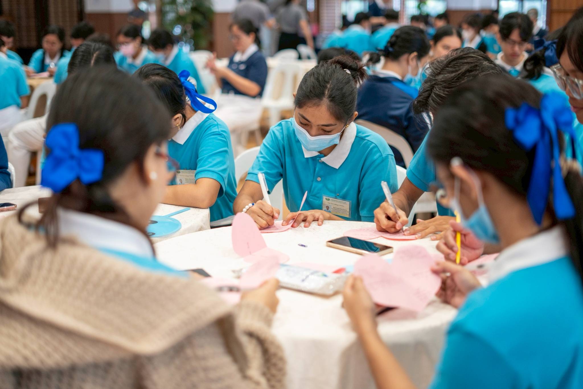 In the activity “From Hearts to Hearts,” scholars wrote their name on a paper heart and passed it on to their seatmate, who wrote a message to that scholar before passing it to their seatmate. The paper hearts were continuously passed and written on until they reached their original owner.