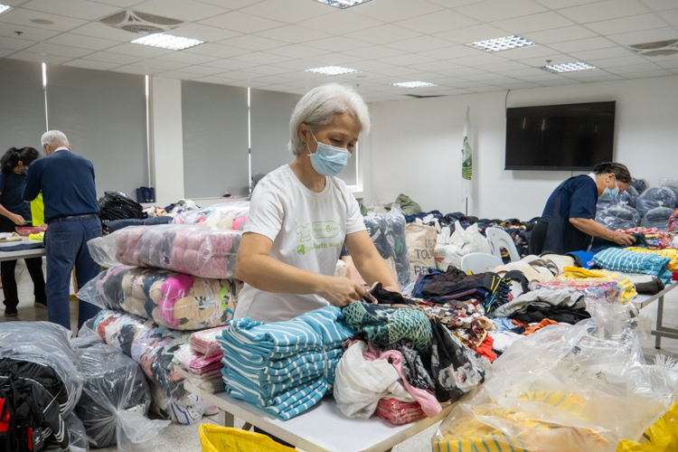 Tzu Chi volunteer Levy Yao works in her station, sorting clothes for the beneficiaries.