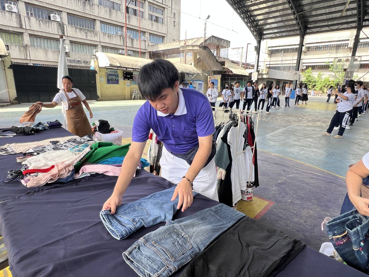 Davidson sets up a display table piled with assorted pre-loved clothes sourced from private donors. . 