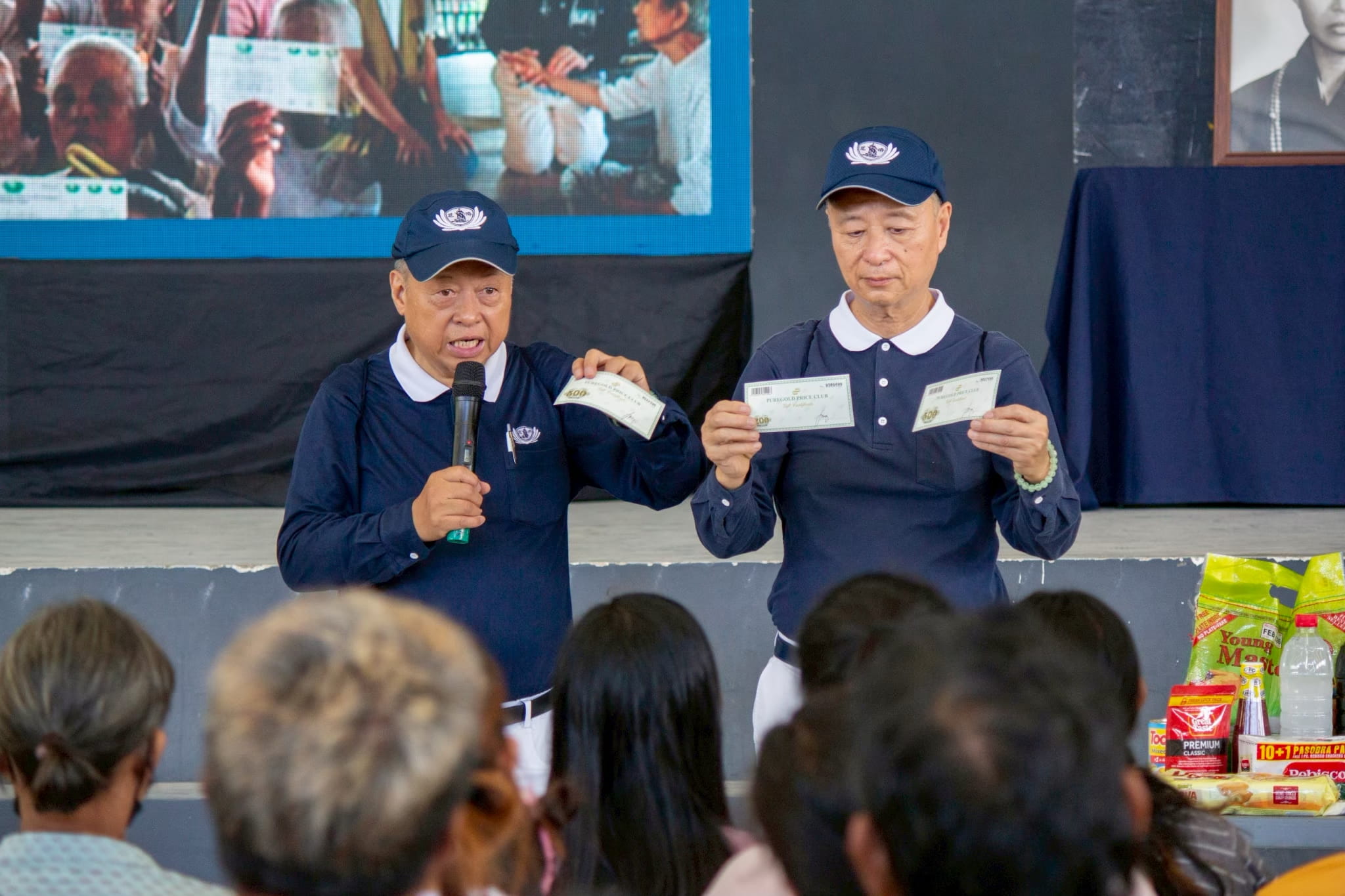 With cousin Luis Diamante (right), Johnny Kwok explains how to use a grocery gift check to beneficiaries at a relief distribution in Iligan, Cagayan de Oro, in the aftermath of Typhoon Basyang (Penha).