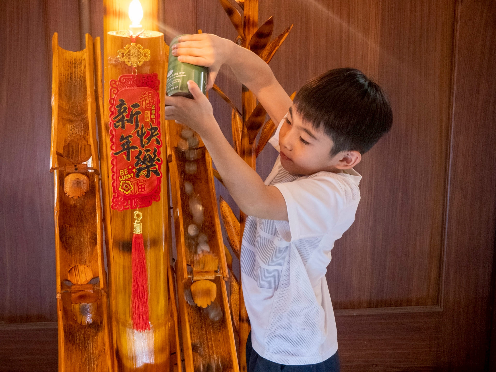 A young guest pours the contents of a Tzu Chi coin can on a bamboo chute. 