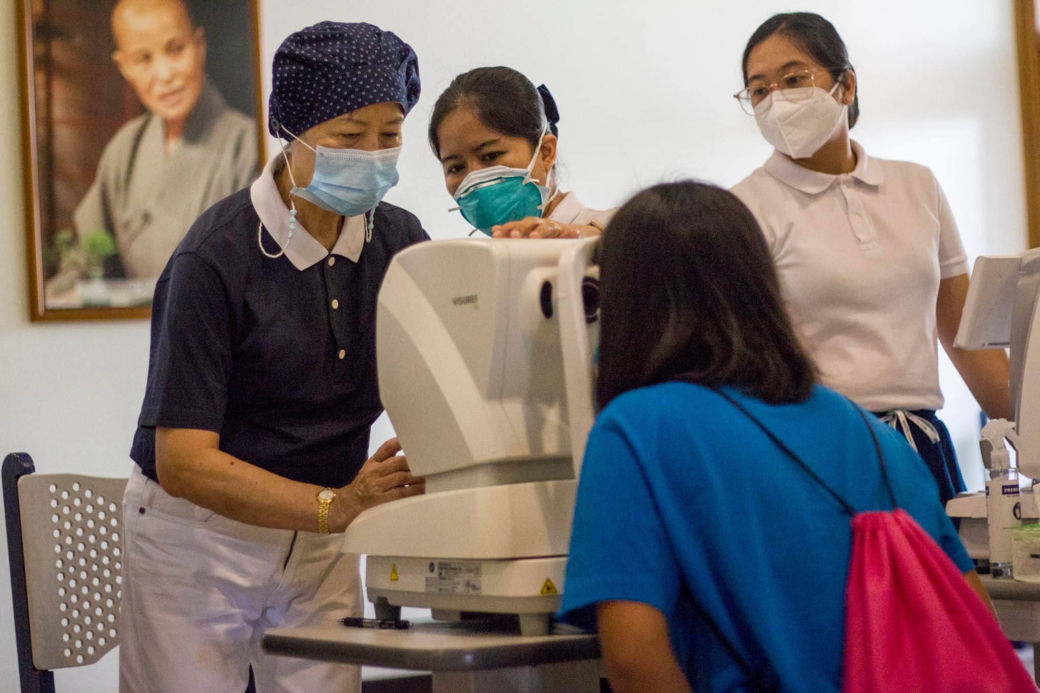 Tzu Chi volunteers look on as a Girlstown student undergoes a refraction test.【Photo by Matt Serrano】