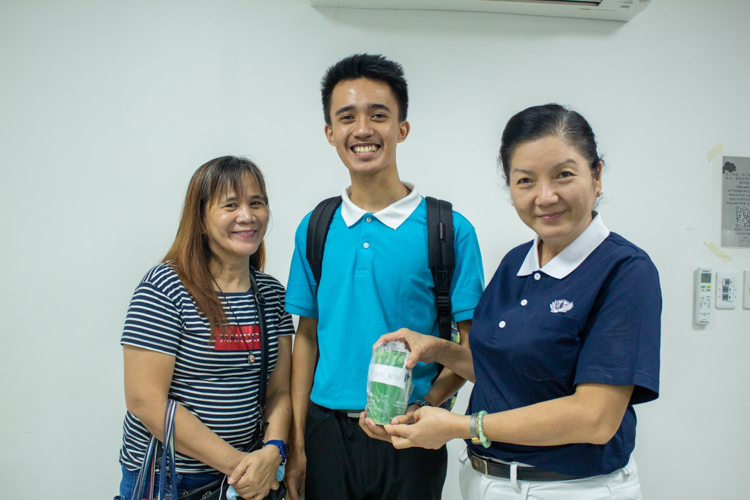 Tzu Chi Education Committee volunteer Rosa So (first from right) receives a coin can donation turned over by Felicitas de los Reyes (first from left), mother of Tzu Chi scholar Edrian de los Reyes (center). 【Photo by Marella Saldonido】