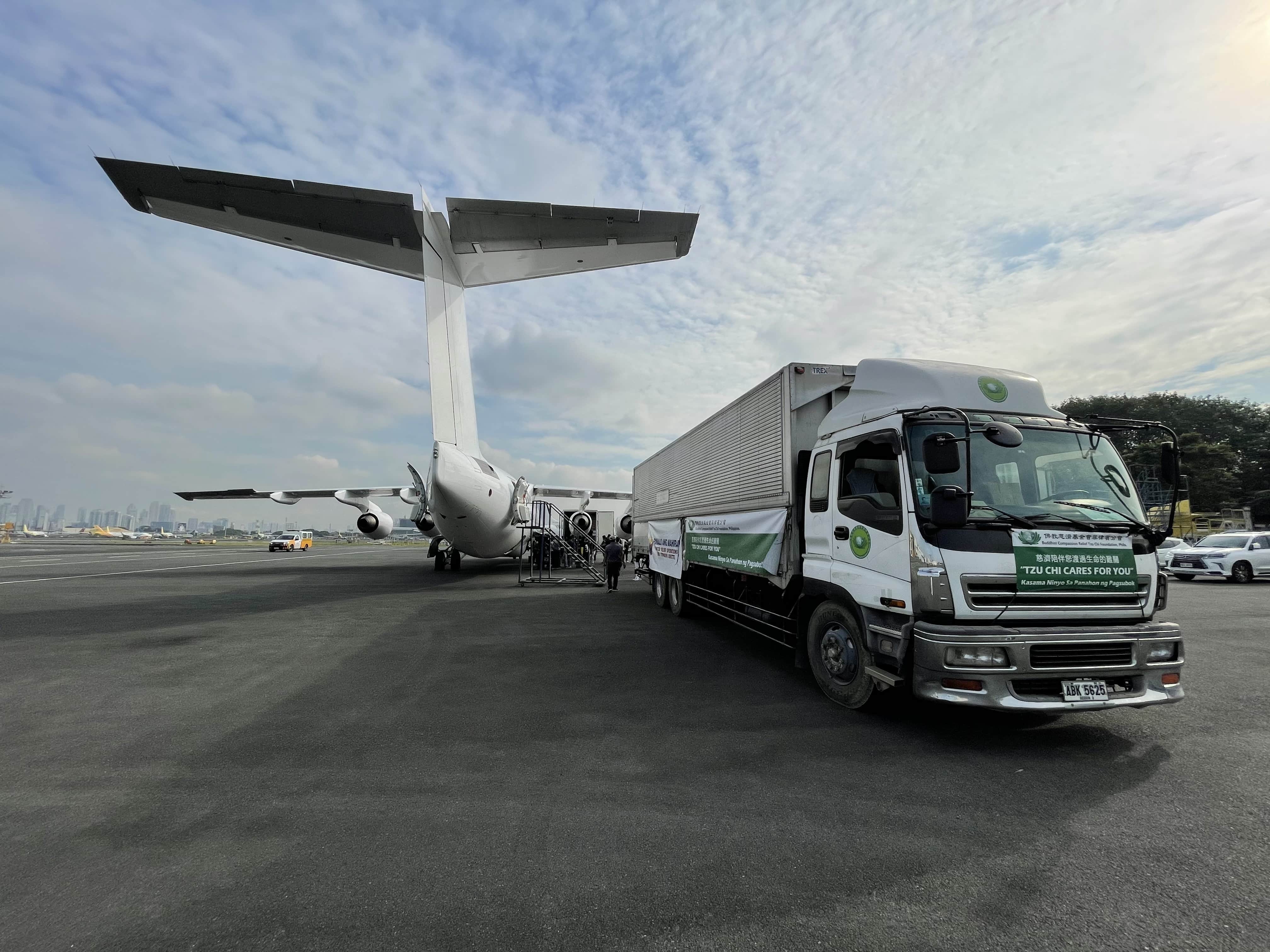 A truck carrying boxes of fleece blankets is parked next to a chartered flight that will take the donations to Tacloban.
