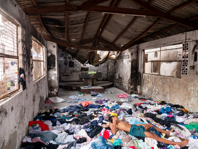A boy lies on a pile of donated clothes inside the Ina ng Laging Saklolo (Mother of Perpetual Help), a neighborhood chapel that was not spared by the fire. 【Photo by Daniel Lazar】