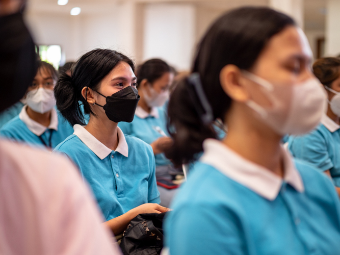 Tzu Chi scholar Jhasmine Yecla (in black mask) listens to a speaker during a short program at the Jing Si Auditorium before the rice distribution.【Photo by Matt Serrano】
