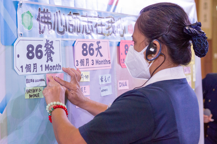 A Tzu Chi volunteer posts her name in a board that enjoins everyone to practice vegetarianism for 86 meals, 86 days, 86 months, 86 years, and 86 lifetimes. 【Photo by Matt Serrano】