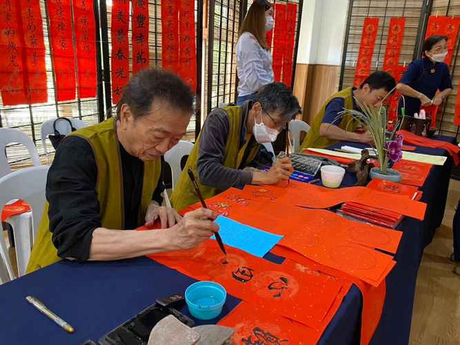 Chinese calligraphy artists write well wishes on red strips of paper. 【Photo by Matt Serrano】