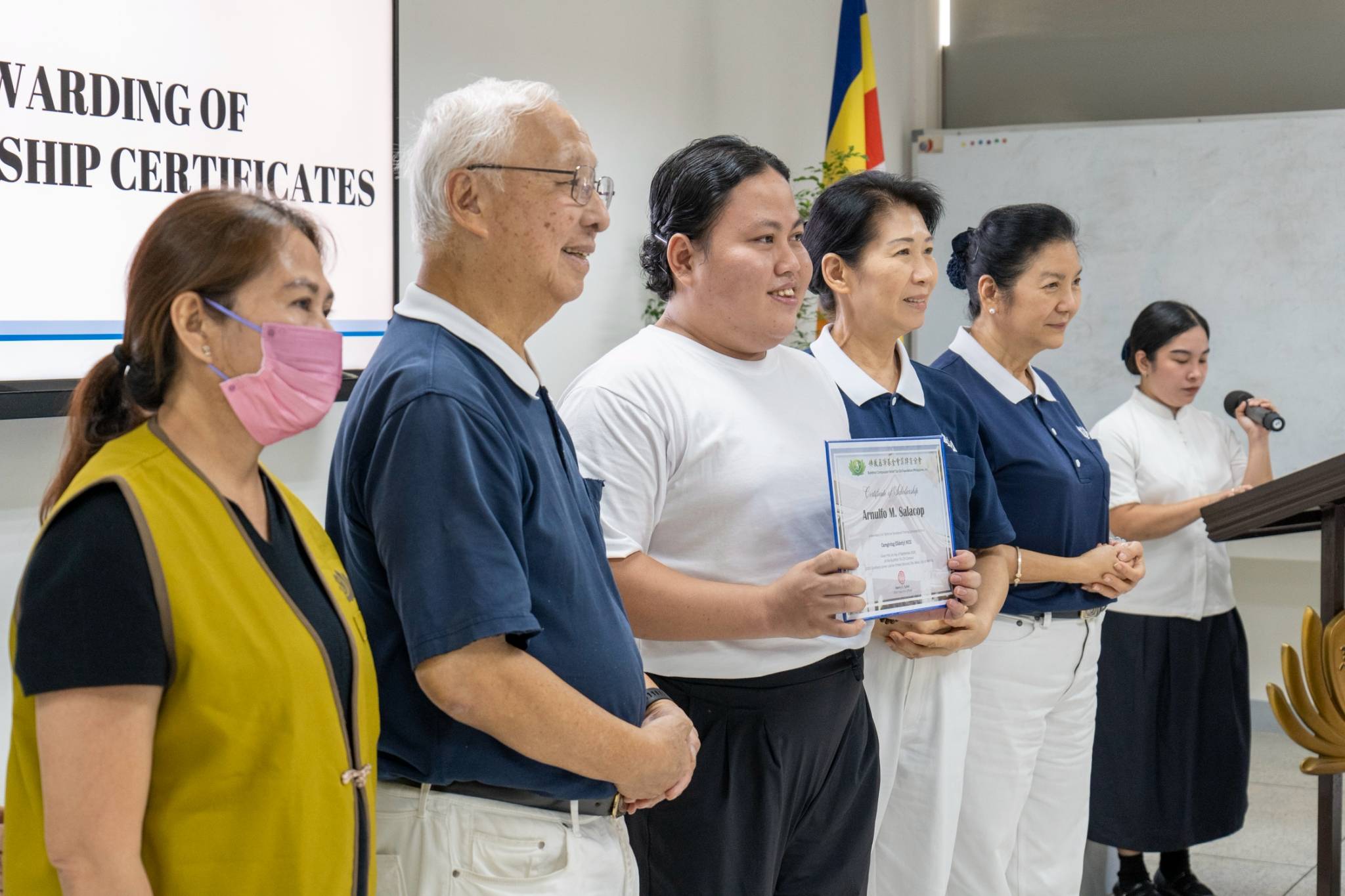 Holding his new opportunity in hand, Caregiving (Elderly) scholar Arnulfo Salacop (third from left) stands proudly with Tzu Chi volunteers upon receiving his scholarship certificate.