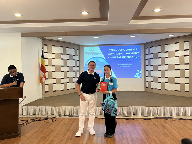 Alexa Labrador (right) receives a backpack and a copy of “Social Welfare and Social Work” by Thelma Lee Mendoza from Tzu Chi Zamboanga OIC and Deputy CEO Dr. Anton Mari Lim.