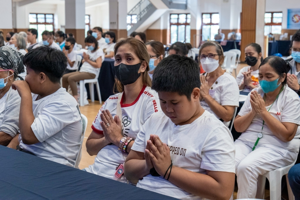 Odessa Jauod (in white shirt with red collar) and son Denver (third from left) participate in prayer during the Charity Day event last March 24.