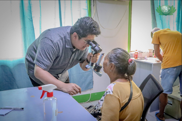 A patient looks into a refractor as Family Eye Care in-house doctor Chris Sasam examines her eyes.
