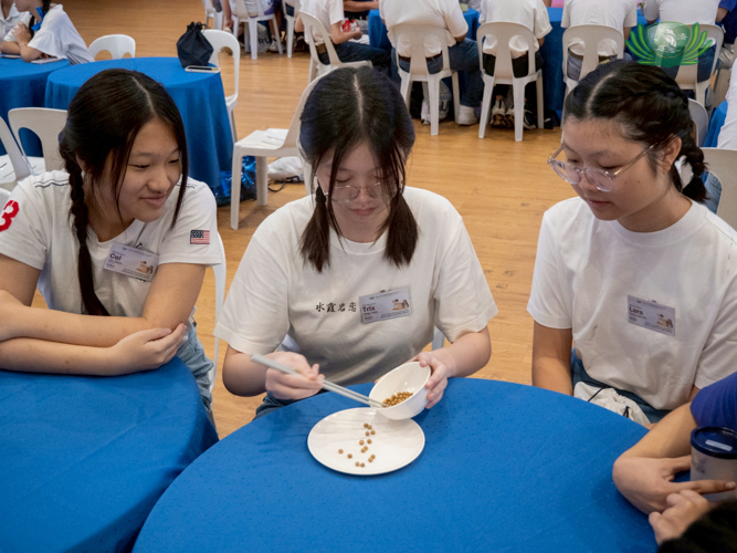 Eating with chopsticks is part of Tzu Chi’s dining etiquette. Participants watch as a groupmate practices using them.