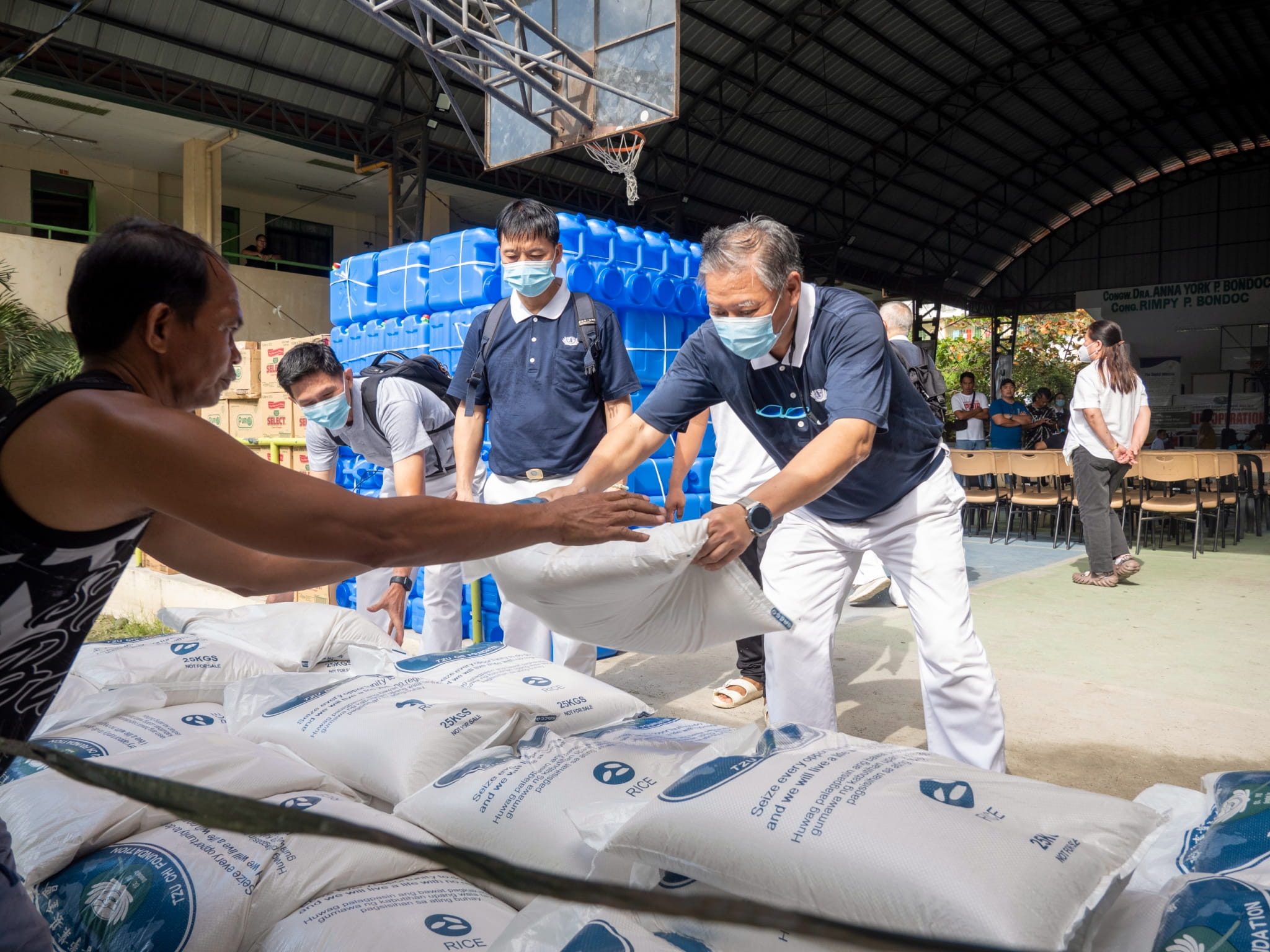 Tzu Chi volunteers help unload sacks of rice for the relief distribution.