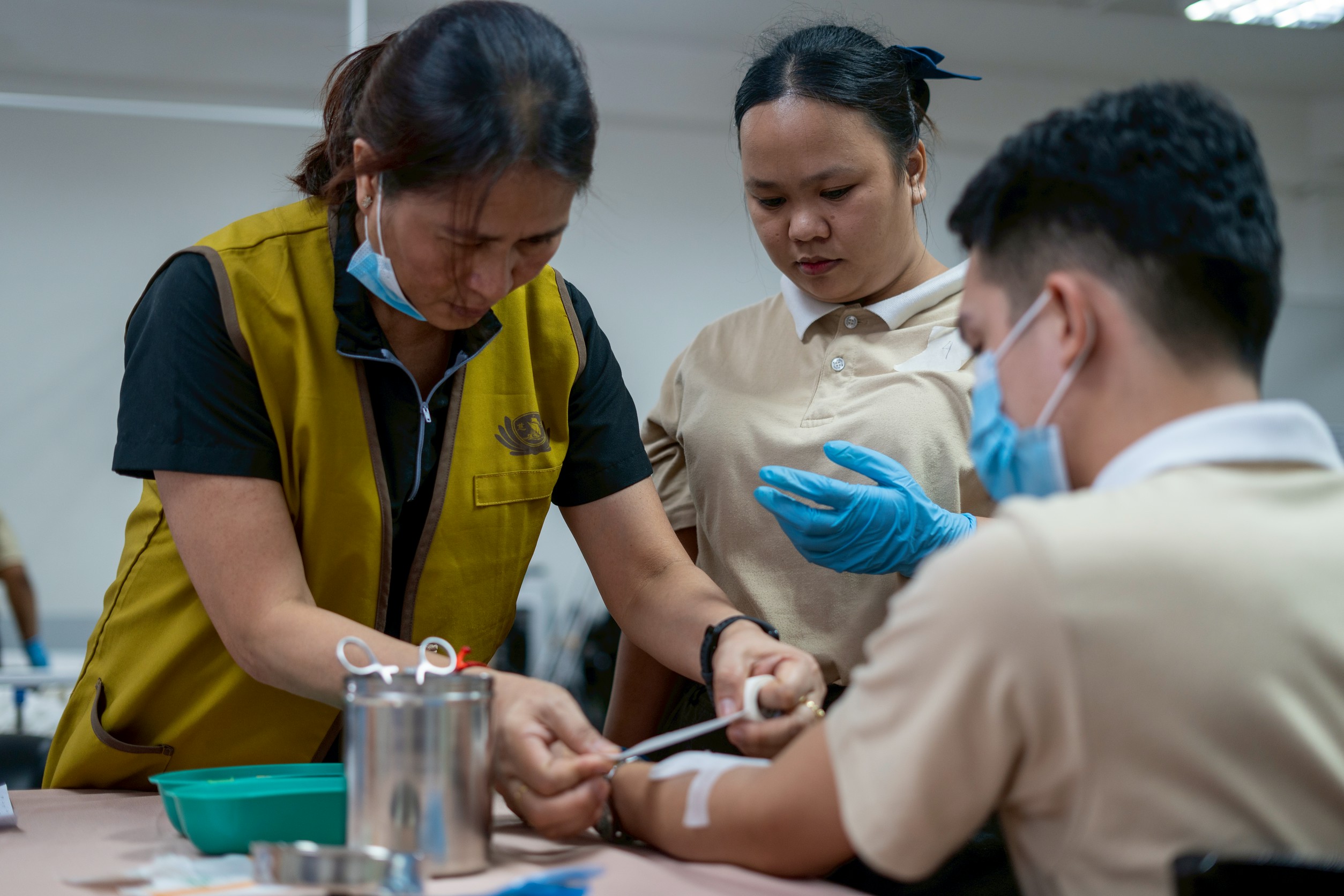 Caregiving students closely observe and follow each step in a hands-on training session conducted by an instructor.