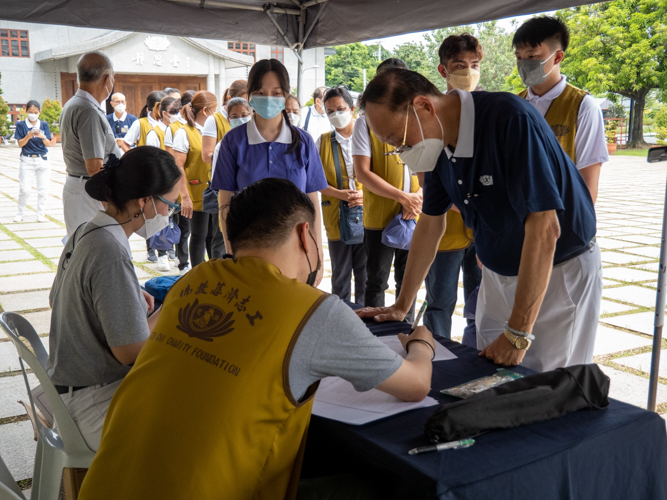 Youth Camp volunteers help Tzu Chi Bicol Coordinator Antonio Tan at the registration area.【Photo by Matt Serrano】