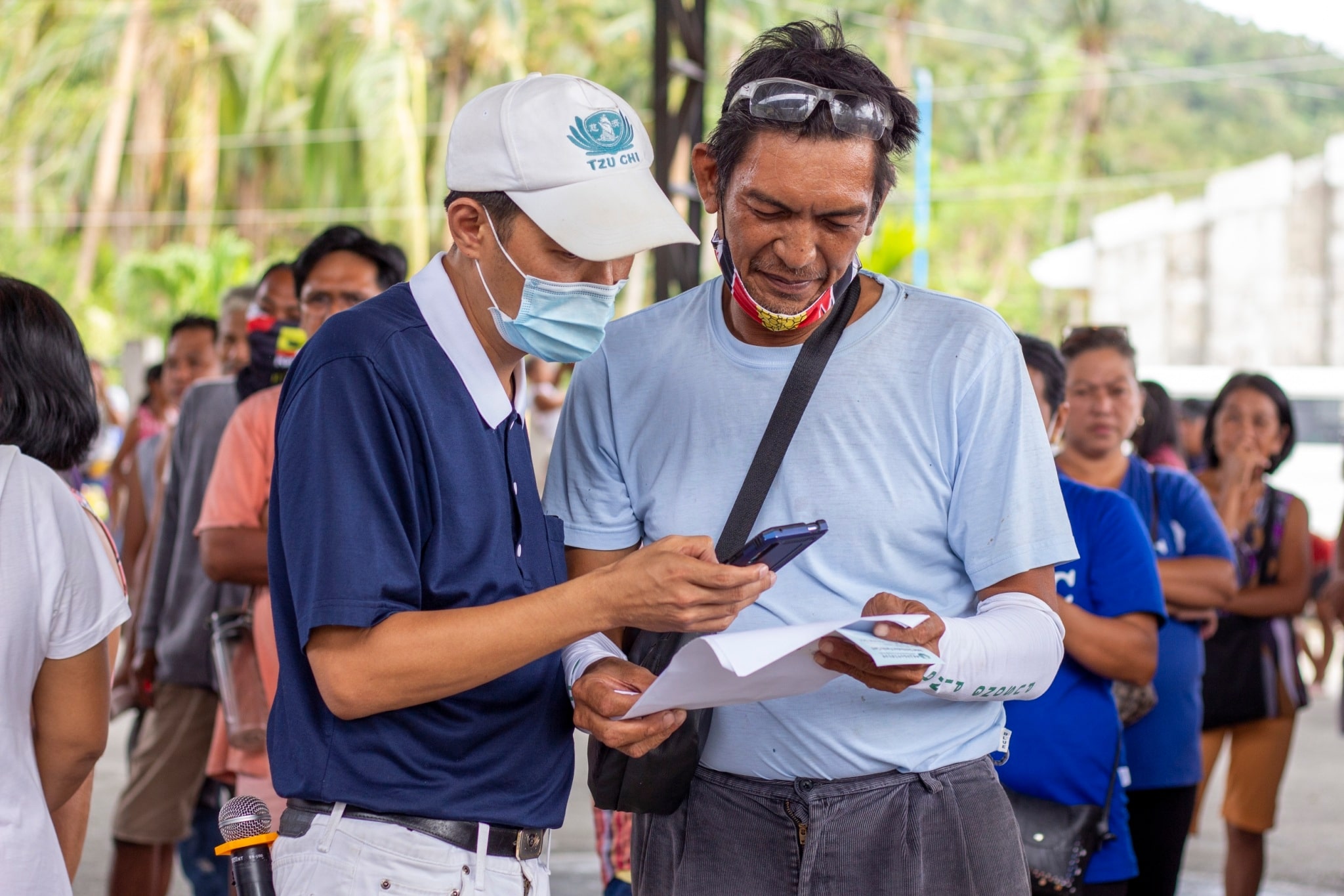 Barangay Paltic resident Tony David (right) is assisted by a Tzu Chi volunteer during relief distribution efforts for Super Typhoon Karding (Noru) survivors.【Photo by Matt Serrano】