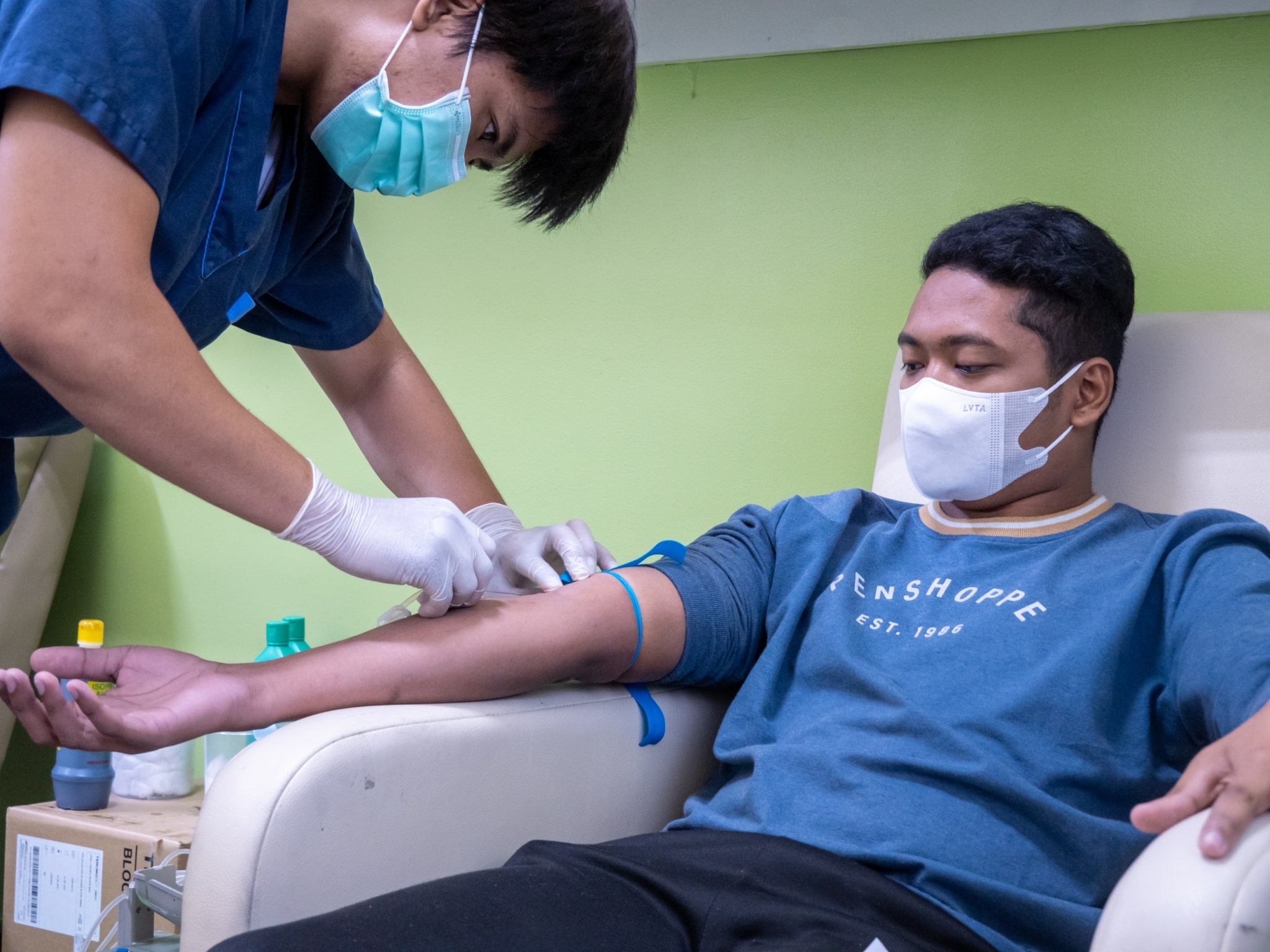 A phlebotomist at the Chinese General Hospital and Medical Center prepares Tzu Chi photographer Matt Adrian Serrano for blood donation.【Photo by Marella Saldonido】