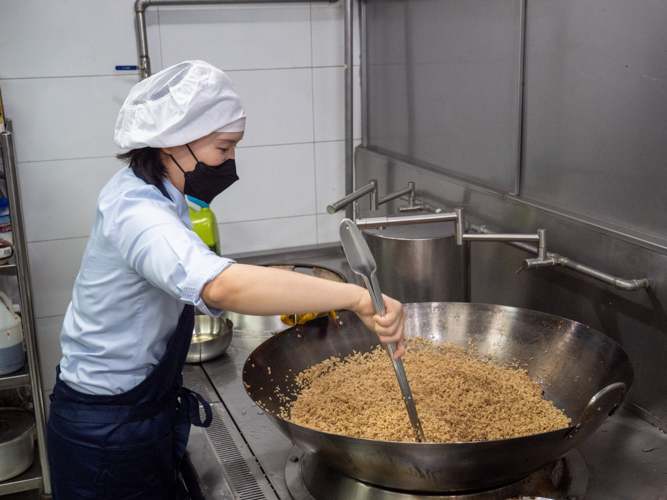 At the Harmony Hall kitchen, stirring the glutinous rice.【Photo by Jeaneal Dando】