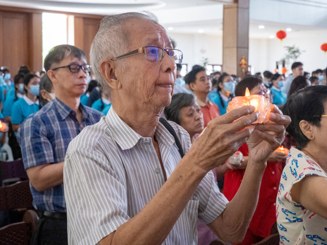 Participants raise a lighted candle as they pray for better things ahead.