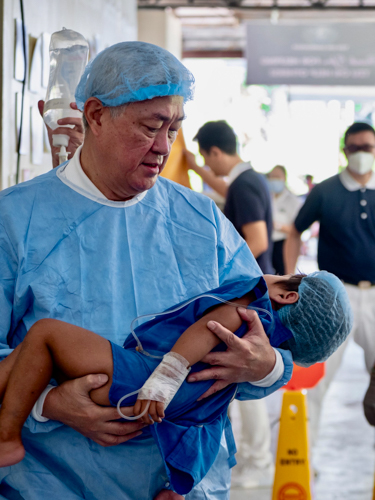 Surgical oncologist and TIMA pioneer Jo Qua cradles a young patient after surgery. Since 1995, Dr. Jo has spearheaded Tzu Chi medical missions all over the Philippines.【Photo by Daniel Lazar】