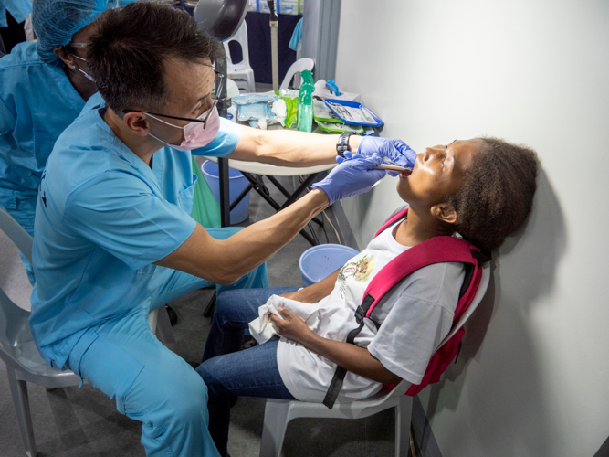 Donna Carpio tilts her head back as a volunteer dentist begins a tooth extraction.