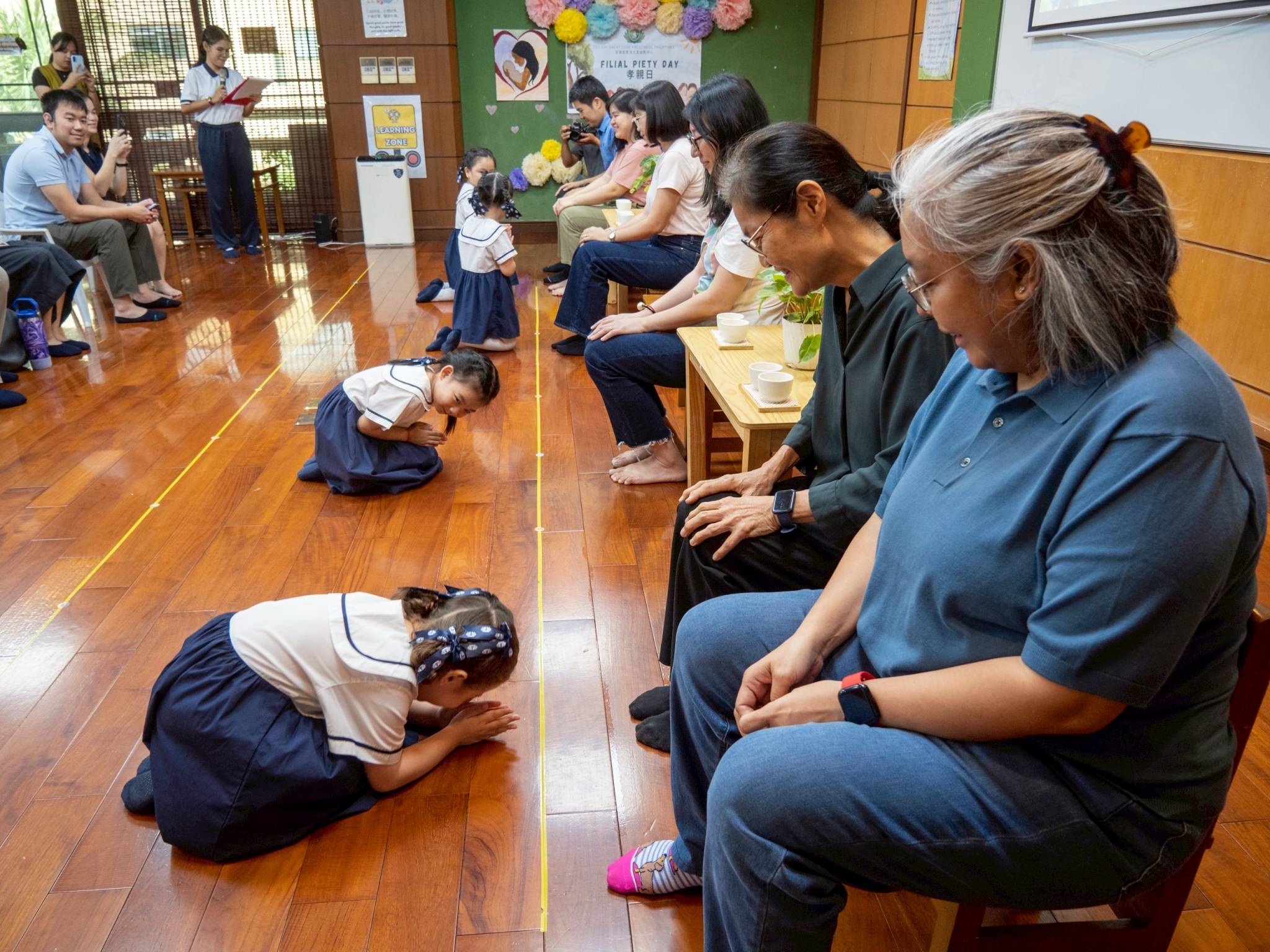 In a humble gesture, the students bowed and knelt before their parents to express their gratitude.