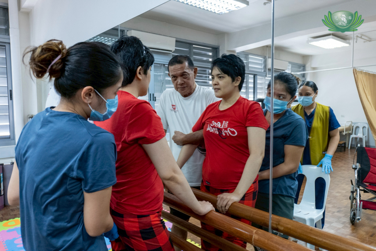 Rica Serrano is held up by her father Ricardo (in white) as she practices standing up.