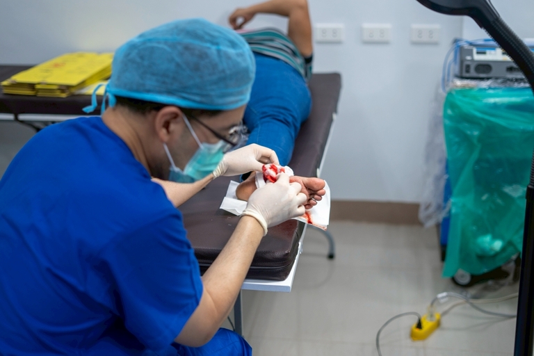 A TIMA surgeon removes a benign cyst on the sole of Arlene Beligan’s left foot. 