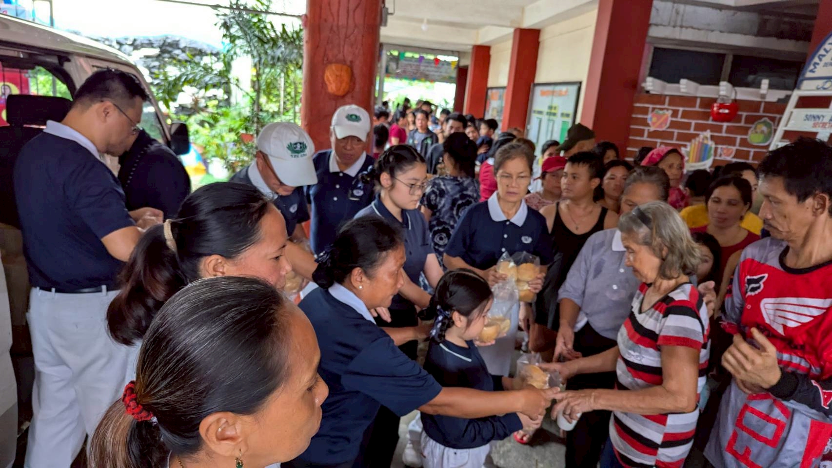 Evacuees at Maly Elementary School in San Mateo, Rizal, eagerly accept bread from Tzu Chi volunteers.