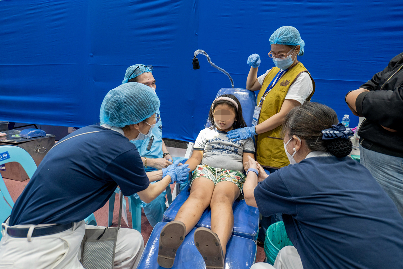 Tzu Chi volunteers calm a nervous little girl during her dental consultation. 