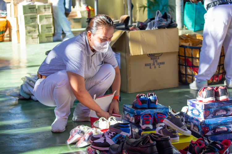 A Tzu Chi volunteer unpacks and arranges shoes to display them for sale at the bazaar. 【Photo by Marella Saldonido】