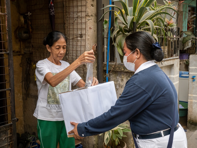 A resident drops coins into Tzu Chi’s donation box for Turkey and Syria. 【Photo by Marella Saldonido】