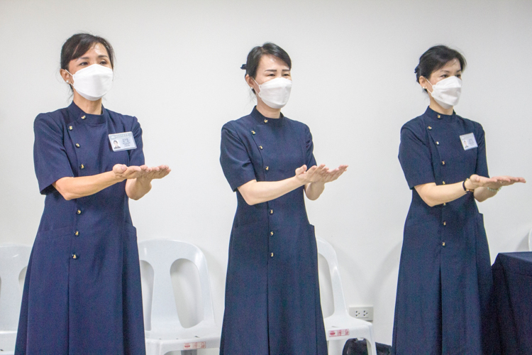 Ang Mei Yuen (first from left) joins other commissioners in leading volunteers to a song in sign language. 【Photo by Matt Serrano】