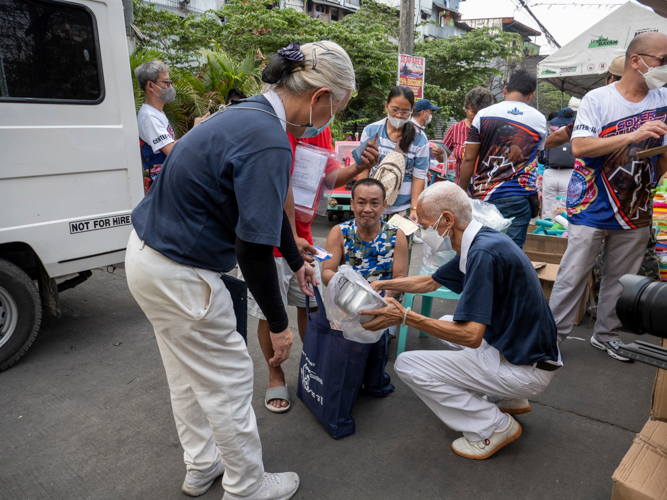 Volunteers place relief goods inside the eco bag of Sandy Sebunga. 【Photo by Matt Serrano】