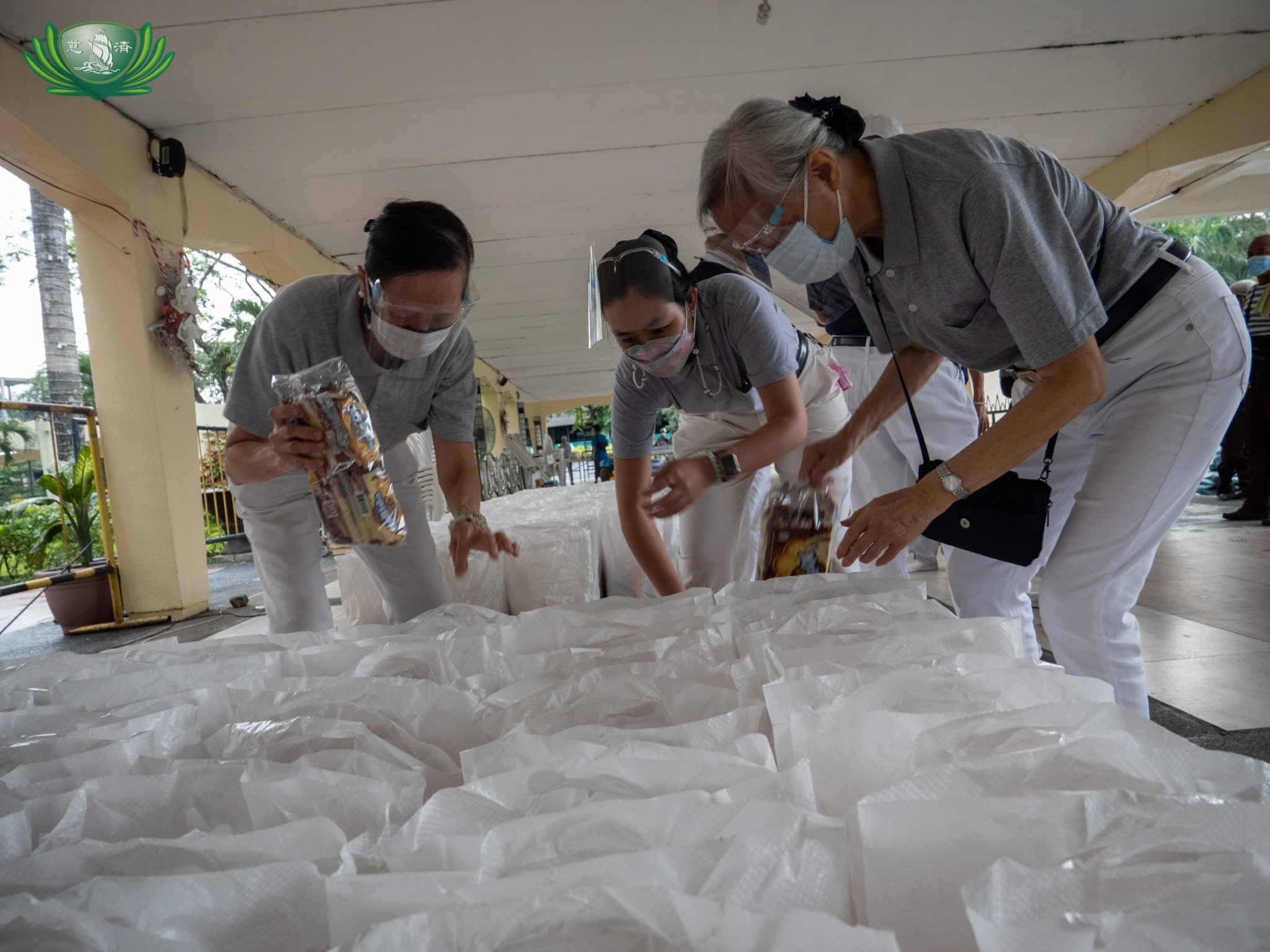 Volunteers prepare bags of groceries to be claimed by the day’s beneficiaries. 【Photo by Jeaneal Dando】