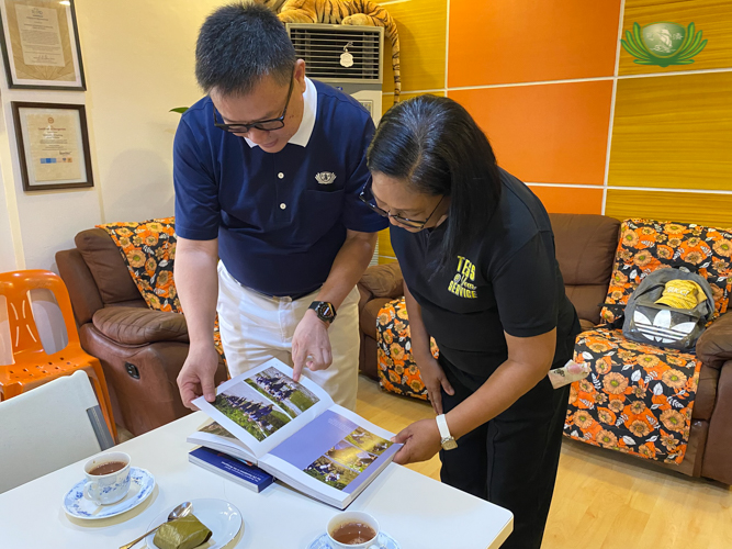 Tzu Chi Davao Officer-in-Charge Nelson Chua (left) shows Kapalong Mayor Maria Theresa Timbol a photo from the book “The Power of Compassion” of volunteers wading through a river to reach the indigenous Talaingod farmers. Through Tzu Chi Davao’s Seed of Change Project, a poverty-alleviating program, these farmers now have a sustainable livelihood from a banana tree-planting initiative launched by Tzu Chi in 2022.